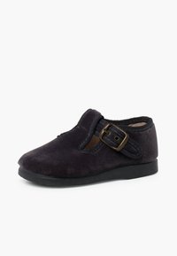 Scarpa in suede viola scuro con punta arrotondata, fibbia decorativa e dettagli elastici. Suola piatta in gomma per stabilità e comfort.