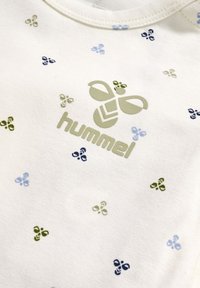 Hvid bomulds T-shirt med små blå og grønne mønstrede detaljer, med et grønt logo, der står "hummel" i midten.