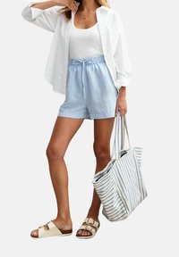 Valkoinen nappipaita, valkoinen toppi, vaaleansiniset shortsit, beiget sandaalit ja raidallinen olkalaukku. Keskittyminen rentoon kesäasuun.