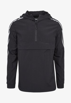 Chaqueta cortavientos negra de manga larga con capucha, cremallera frontal hasta la mitad, puños elásticos y rayas blancas que recorren cada manga.
