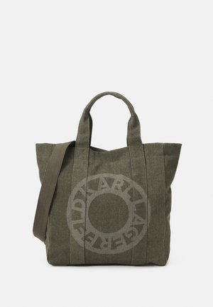 Grand sac cabas en toile vert olive avec double poignée, bandoulière et logo imprimé circulaire à l'avant.