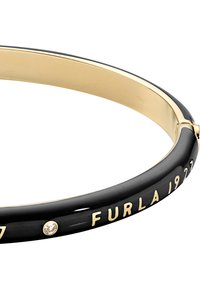 Must bangle-käevõru, millel on kuldne sisemus, millel on graveeritud tekst "FURLA 1927" ja väike selge vääriskivi aktsent. Sile viimistlus.