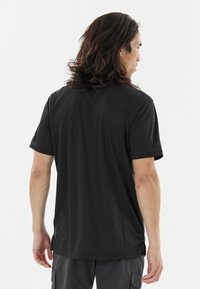 Sort kortærmet t-shirt lavet af blødt stof, med en afslappet pasform og subtile sideslids for nem bevægelse.