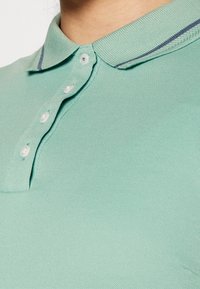 Světle modrá polokošile s žebrovaným límečkem s kontrastním pruhem, pětiknopovým zapínáním a texturovanou látkou.