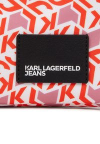 Raudonos ir baltos raštuotos medžiagos audinys su juodais odiniais įsiuvais. Įsiuvai turi užrašą "KARL LAGERFELD JEANS" baltomis raidėmis.
