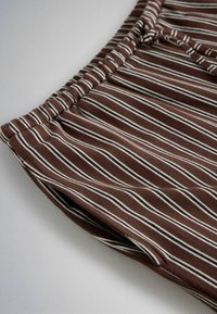 Brown fabric with vertical white and black stripes, featuring a gathered elastic waistband and a side pocket opening.