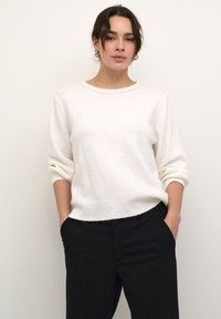 Maglione bianco a maglia con scollatura rotonda e spalle.Drop. Tessuto morbido, vestibilità casual, abbinato a pantaloni sartoriali scuri.