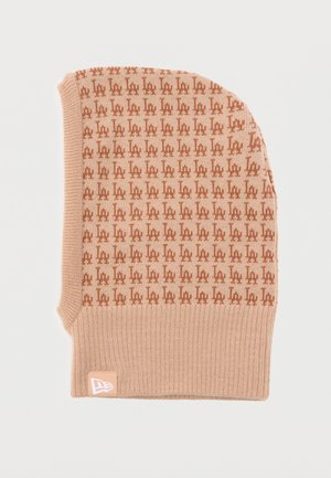 Beige en bruin gebreide bivakmuts met herhaald "LA" patroon en een klein wit logolabel aan de geribbelde onderkant.