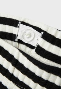 Zwart-wit gestreepte stof met ribbelstructuur; beschikt over een witte knop en stikseldetail aan de bovenrand.