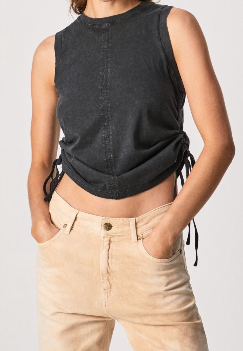 Svart, ärmlös crop top med rund halsringning, med sidodragband och kontrasterande sömmar. Matcher med ljusa, högmidjade byxor.