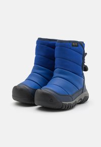 Niebieskie wodoodporne buty z pikowaną fakturą, zaokrąglony czubek, szara gumowa podeszwa, regulowany sznurek z tyłu oraz czarny akcent z logo.