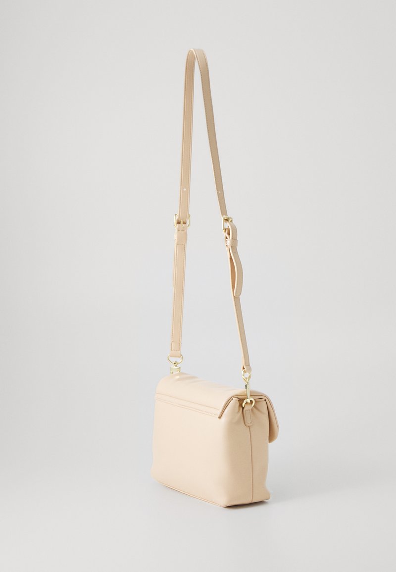 Beige Umhängetasche aus glattem Material mit umgeschlagenem Oberteil, verstellbarem Trageriemen und Hardware in Goldoptik. Kompakte rechteckige Form.