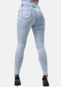 Jeans skinny de mezclilla azul claro con cintura alta, diseño de cinco bolsillos y bolsillos traseros. Textura suave con un ligero desgaste y sin patrones visibles.