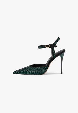 Scarpa con tacco alto a punta in suede nero, adornata con strass verdi, con cinturino alla caviglia e fibbia dorata e tacco a spillo.