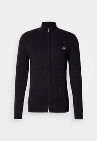 Fekete kötött pulóver cipzárral, kábelmintás dizájnnal, bordás mandzsettákkal és gallérral. Ezüst cipzár részlet és kis logó a mellkason.