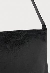 Borsa in pelle nera con finitura texture, dotata di chiusura con zip e tracolla piatta. Il design presenta una silhouette semplice e pulita.