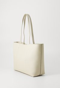 Borsa tote in ecopelle crema con doppi manici lunghi, forma rettangolare strutturata e dettaglio di cucitura minima sul davanti.