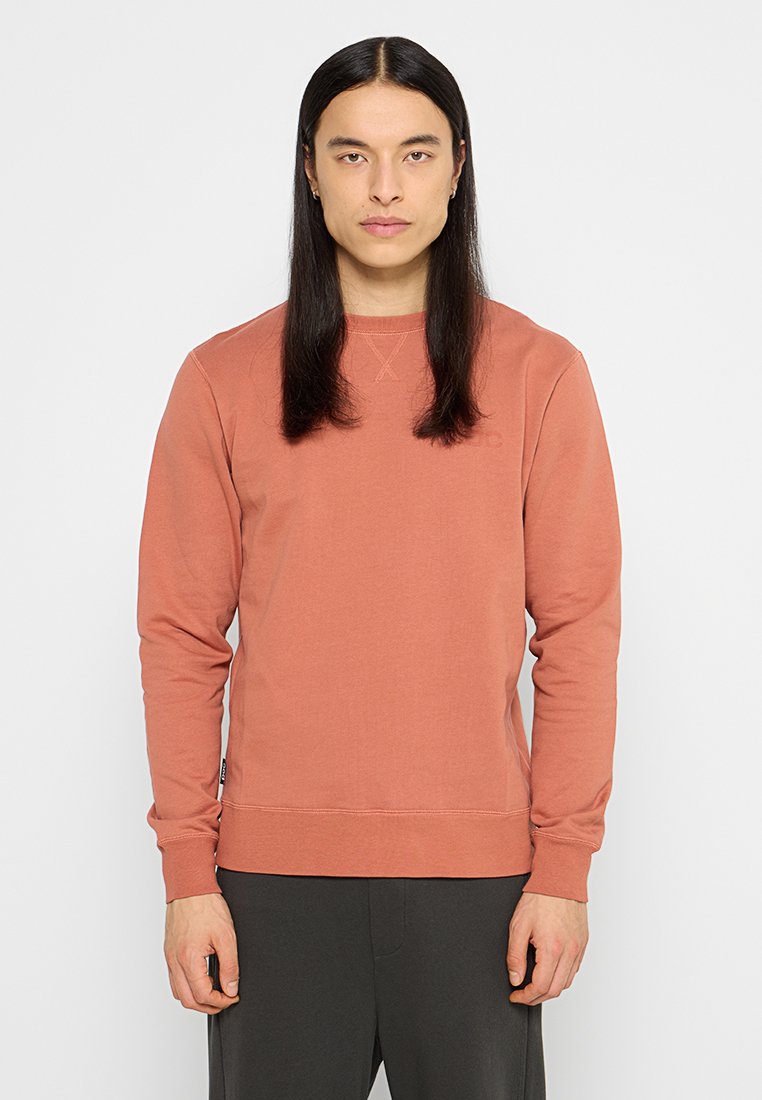 Rostfärgad sweatshirt gjord av mjuk bomullsmix. Har rund halslinning, långa ärmar och ribbade ärmmuddar med subtila sömdetaljer.