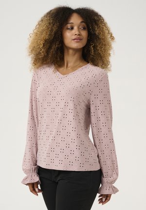 Light pink long-sleeve blouse featuring a stitched eyelet pattern, V-neckline, and ruffled cuffs, set against a neutral background.