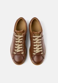 Brown leather sneakers with a rounded toe, beige laces, and embossed branding on the tongue. Textured surface and cushioned interior.