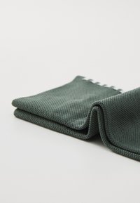 Grön texturerad tygvikning med ett vävt mönster och en slät kant, med en ren finish och en jämn, dämpad färg genomgående.