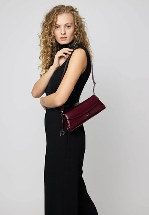 Burgundy leather crossbody bag with a fold-over flap, silver hardware, and a detachable strap. Features a smooth texture and minimalist design.