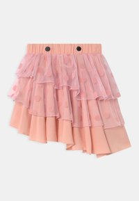 Jupe rose à plusieurs couches avec un overlay en tulle froncé comportant des pois. Taille élastique avec deux boutons noirs, ourlet asymétrique.