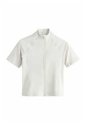 Rövid ujjú, fehér cipzáras felső magas gallérral és varrási részletekkel elől és az ujjakon, egyszerű háttéren bemutatva.