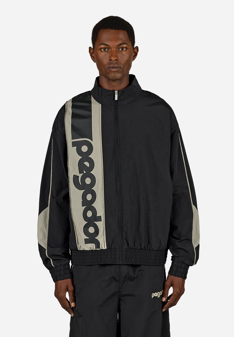 Μαύρο μπουφάν bomber μ�ε ψηλό γιακά, γκρι λεπτομέρειες και μεγάλο λογότυπο "pegador" στο πλάι. Διαθέτει ελαστικές μανσέτες και φερμουάρ μπροστά.