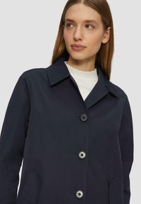 Marineblauwe, lichtgewicht jas met een kraag, vier knopen aan de voorkant en zijzakken. Glad textuur, minimalistisch design, moderne pasvorm.