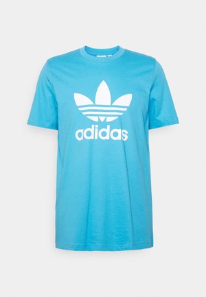 Niebieski t-shirt z krótkim rękawem, okrągłym dekoltem oraz dużym białym logo i napisem Adidas na środku przodu.