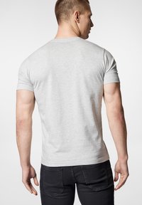 Szara bawełniana koszulka z krótkim rękawem, okrągłym dekoltem i dopasowanym krojem. Noszona z czarnymi dżinsami; widok pokazuje plecy. Prosta i gładka tekstura.