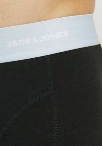 Fekete pamut boxer alsónadrág világoskék rugalmas derékpánttal, amelyen a "JACK & JONES" felirat fehér színben szerepel. Simaság jellemzi, testhezálló kialakítással.