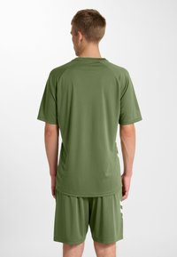 Kortemouwen sportshirt en korte broek in olijfgroen. Gladde, lichtgewicht stof met een ontspannen pasvorm en een afgeronde zoom, voorzien van zijsplitten.