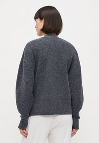 Grau gestrickter Pullover mit einem hohen Rippkragen, schulterfreien Ärmeln und gerippten Bündchen. Weiche Textur und lässige Passform, entworfen für Komfort.