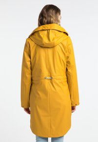 Gul vattentät jacka med huva, med dragsko i midjan, långa ärmar och en slät, glänsande yta. Minimalistisk design, utan mönster.