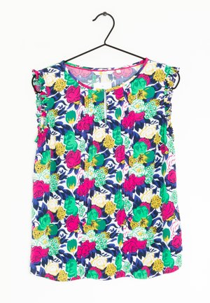 Top à imprimé floral avec des manches volantes, présentant un motif multicolore en rose, vert, jaune et bleu sur un fond blanc.