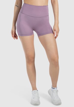 Lila high-waisted sportshorts gemaakt van rekbaar materiaal, met platte naden en een gladde textuur, gecombineerd met witte sportschoenen.