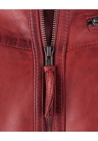 Rode leren jas met een zilveren rits, een gestructureerd oppervlak en een klein zakje op de linker borst met een ritsen trekker.