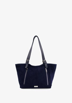 Marineblå suede tote taske med to lynlås-lommer, dobbelt teksturerede stropper og metallisk logo-plade. Bred form med blødt, holdbart materiale.