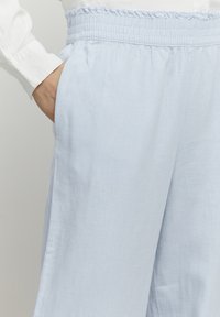 Lichtblauwe broek met een ontspannen pasvorm, voorzien van een elastische tailleband en zijzakken, gemaakt van zachte, ademende stof.