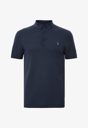 Tummansininen polo-paita, joka on valmistettu pehmeästä kankaasta. Paita sisältää kauluksen, kolme nappia ja pienen embleemin vasemmassa rinnassa. Lyhyet hihat.