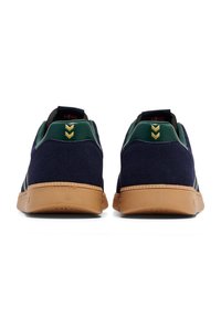 Blå mockaskor med gröna hälackenter, grå mesh-tunga, gummigummisulor och guld detaljer på baksidan.