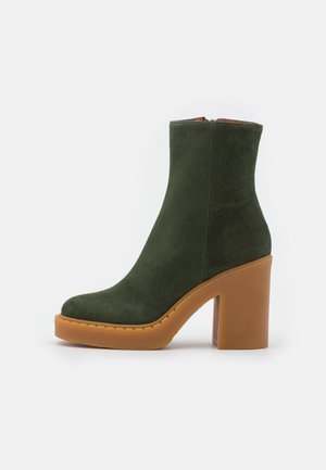 Bottine en suède vert olive montant à la cheville avec talon bloc épais marron clair et semelle plateforme, fermeture éclair latérale.