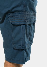 Navy blue cargo shorts made from lightweight fabric featuring a side pocket with button closure and stitched detailing on the hem.