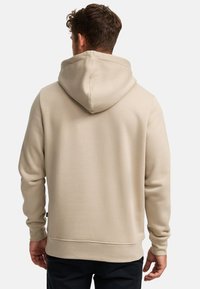 Beige capuchontrui met een gladde textuur, voorzien van een grote capuchon en geribbelde manchetten aan de mouwen en zoom.