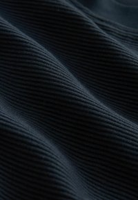 Musta ribattukangas, jossa on pehmeä tekstuuri ja vahvat vaakaviivat, mikä luo syvyyttä ja hienovaraisia varjoja.