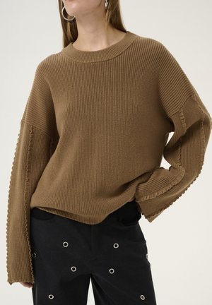 Brown ribbed knit sweater with long sleeves and frayed hem details. Paired with black pants featuring silver grommet accents.