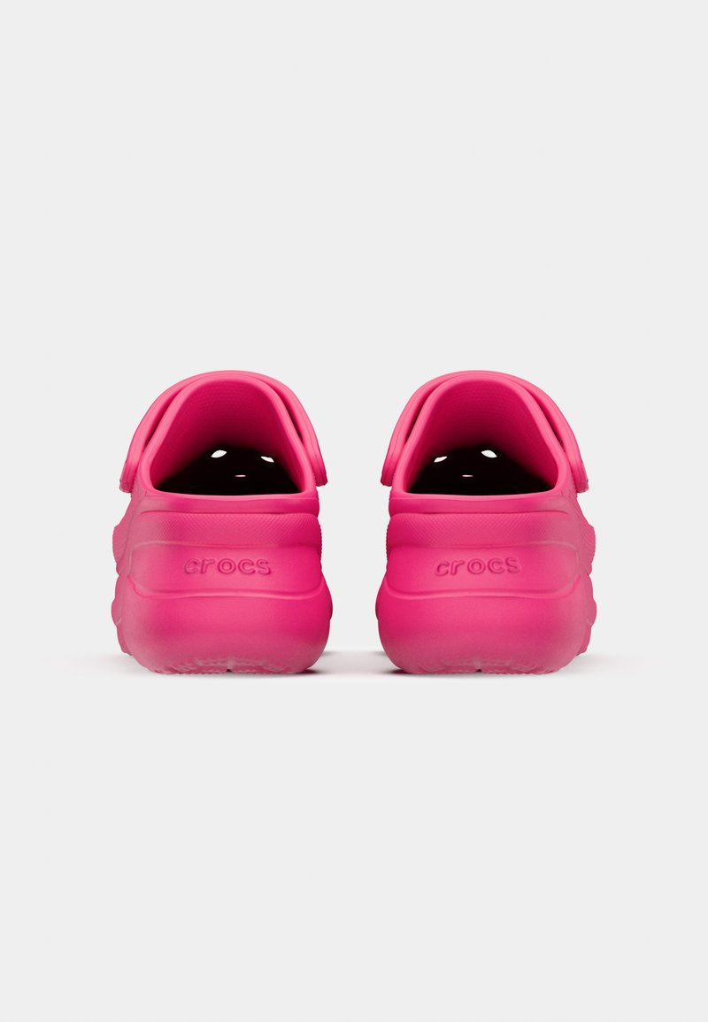 Rosa Crocs mit einer glatten Textur, Fersenriegel und Belüftungsöffnungen. Logo auf der Rückseite eingeprägt. Leicht und rundes Design.