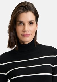 Schwarzer Rollkragenpullover mit weißen horizontalen Streifen. Stricktextur, taillierte Passform, verfügt über einen gerippten Kragen und gerippte Ärmelabschlüsse.